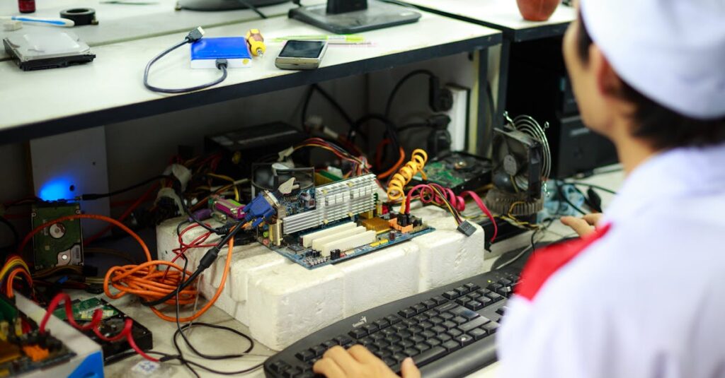 A man in a laboratory uniform working on computer components and wiring at a workstation.