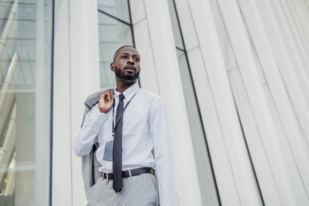 Businessman in formal attire posing in front of modern office building facade.