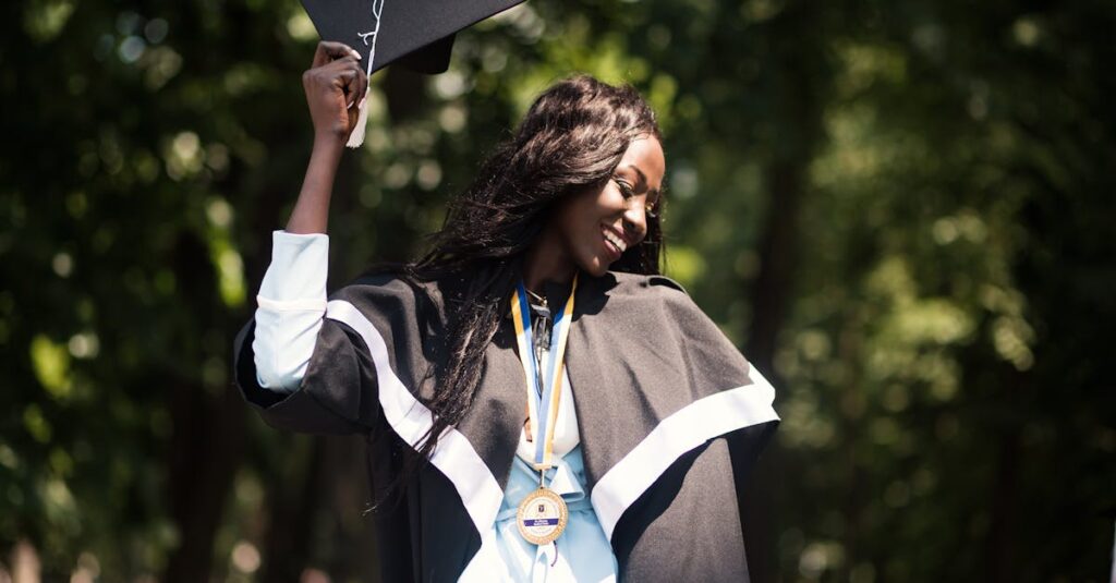 A woman in academic dress celebrates her graduation in a sunny park.