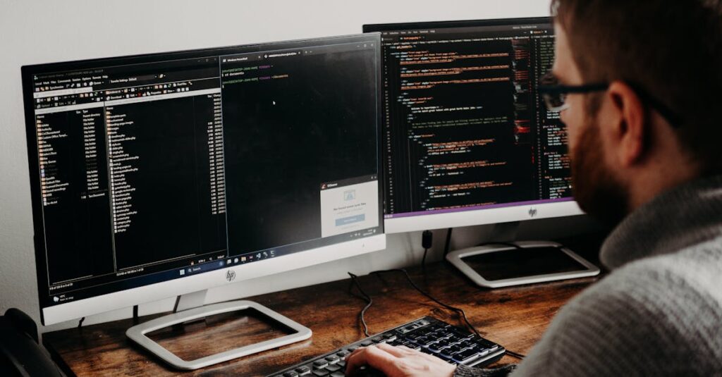 Software developer typing code on dual monitors at a wooden desk.