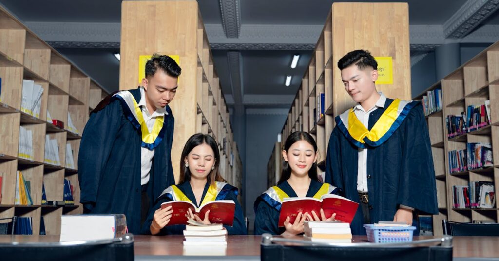A group of university graduates in academic gowns study together in a library.