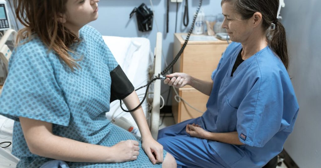 A nurse in blue scrubs checks the blood pressure of a female patient in a hospital room.