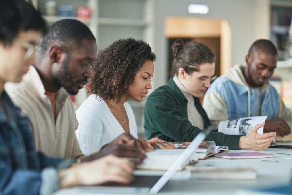 Student Advisory Multiracial group of college students studying together indoors in a library.