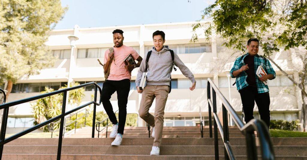 Tuition & Aid Three college students walk down stairs on campus, carrying books and backpacks, on a sunny day.