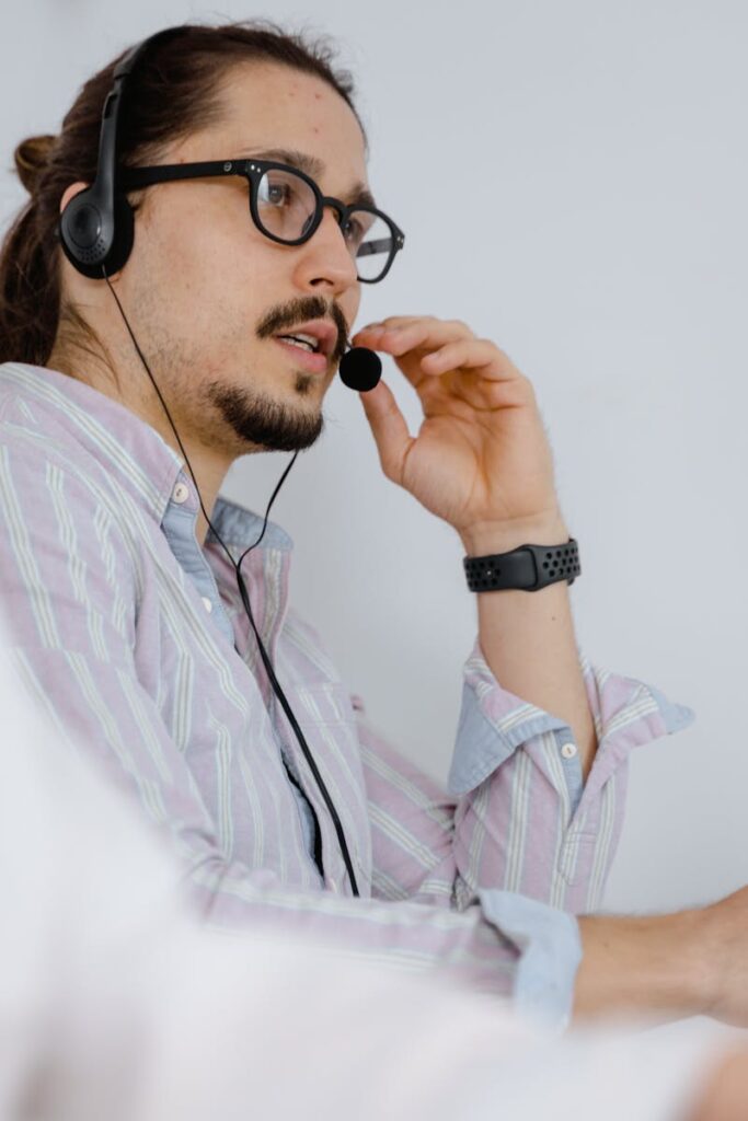 Focused customer service agent speaking on a headset in a modern office environment.
