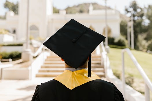 Scholarships Back view of a graduate in a cap and gown standing outdoors facing a building.