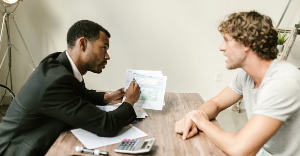 A financial advisor discusses paperwork with a client at a desk in a modern office.