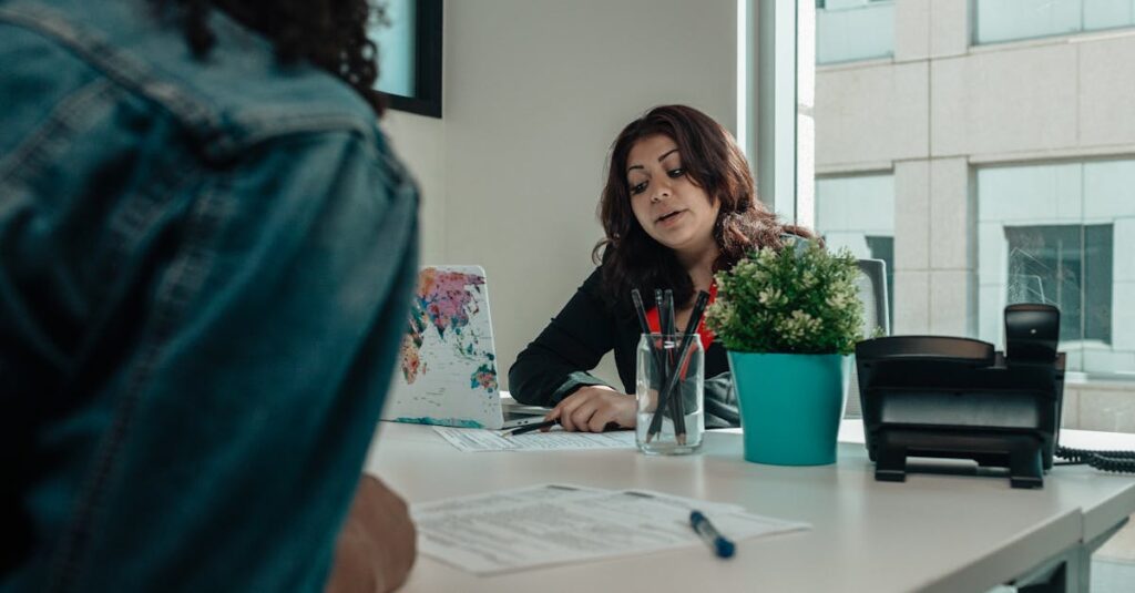 Tuition & Aid Two individuals in an office engaged in a discussion with paperwork.