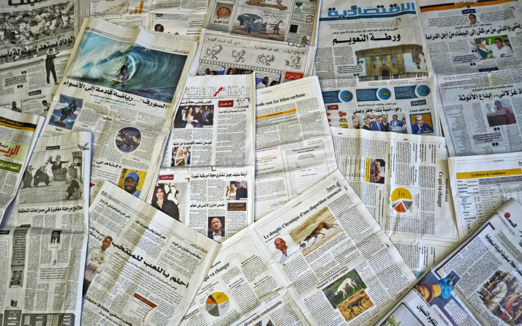 A variety of Arabic newspapers laid out, showcasing cultural and news diversity in Fès, Morocco.